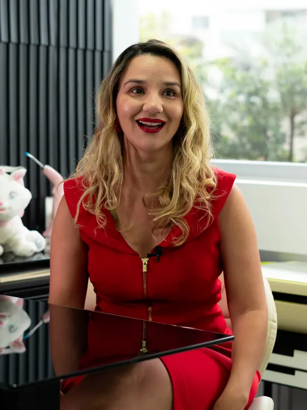 Dra. Érica Mello de vestido vermelho no consultório