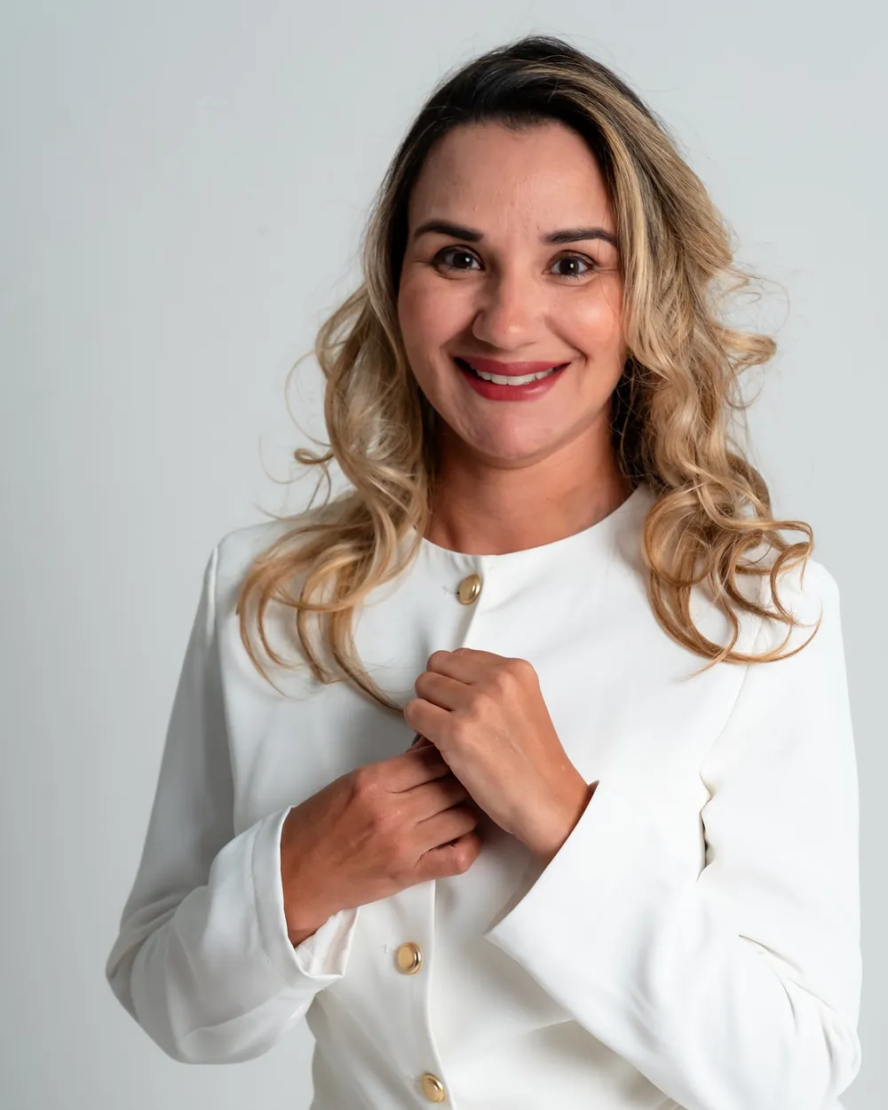 Dra. Érica Mello, cirurgiã-dentista, sorrindo, de conjunto branco