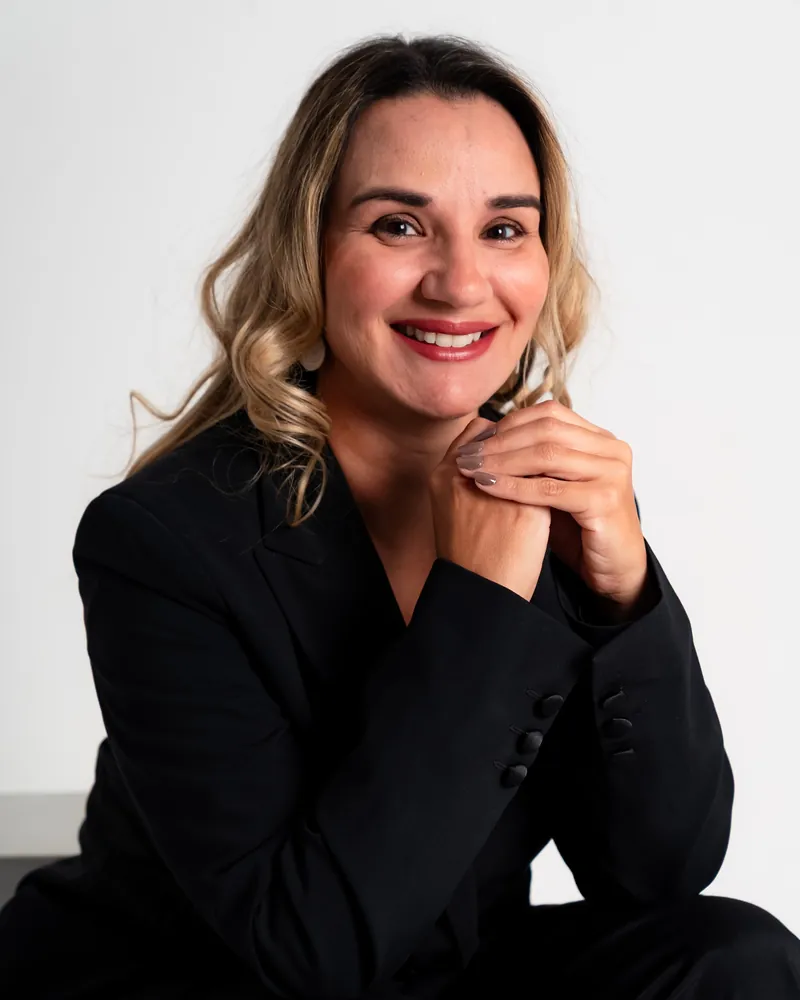 Dra. Érica Mello sorrindo, de blazer preto